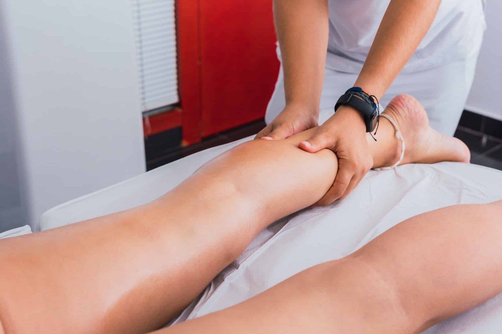 Massage therapist massaging woman calf in spa center
